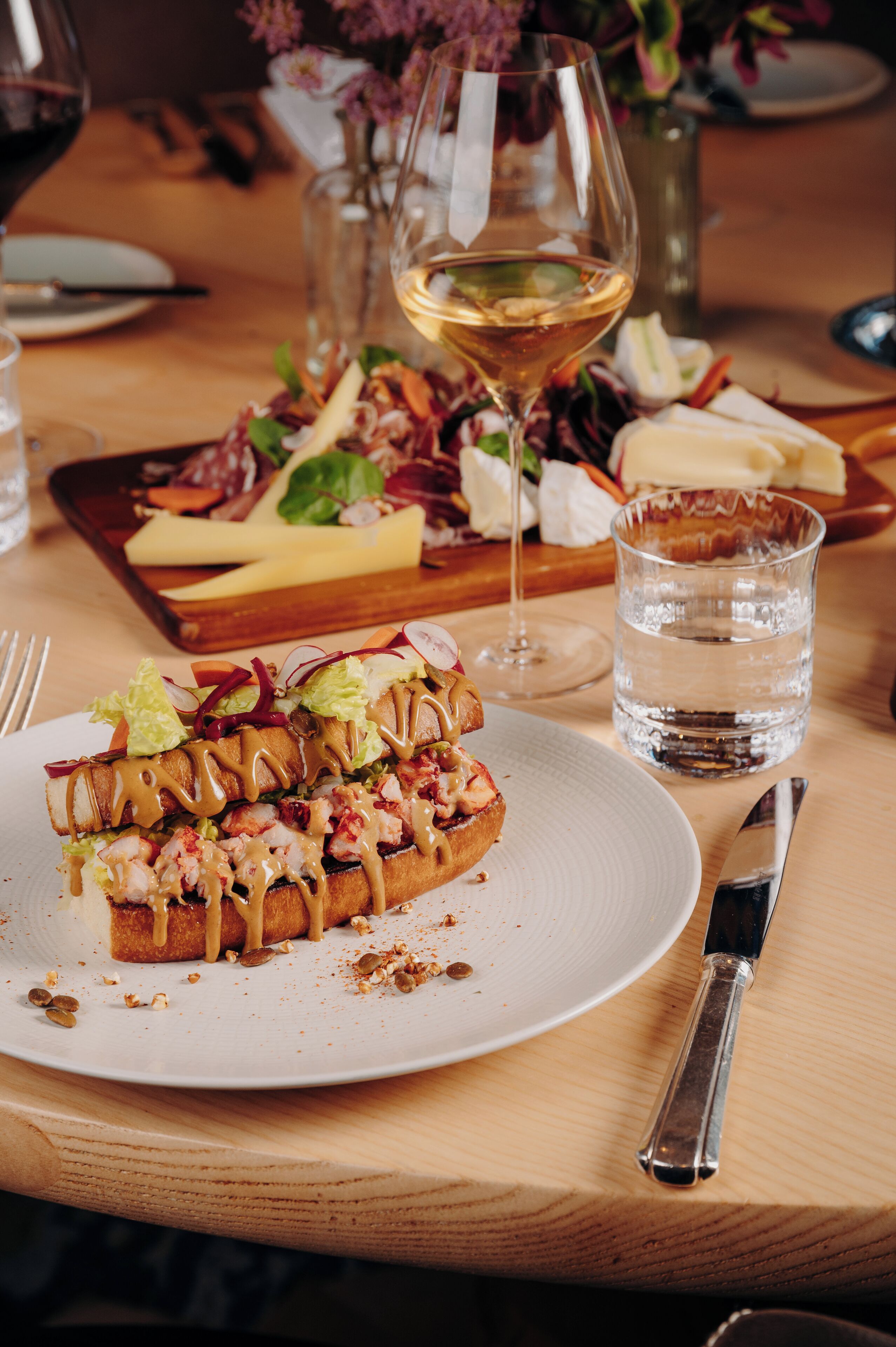 A dining table with a plate of food, a glass of water, and a wine glass.