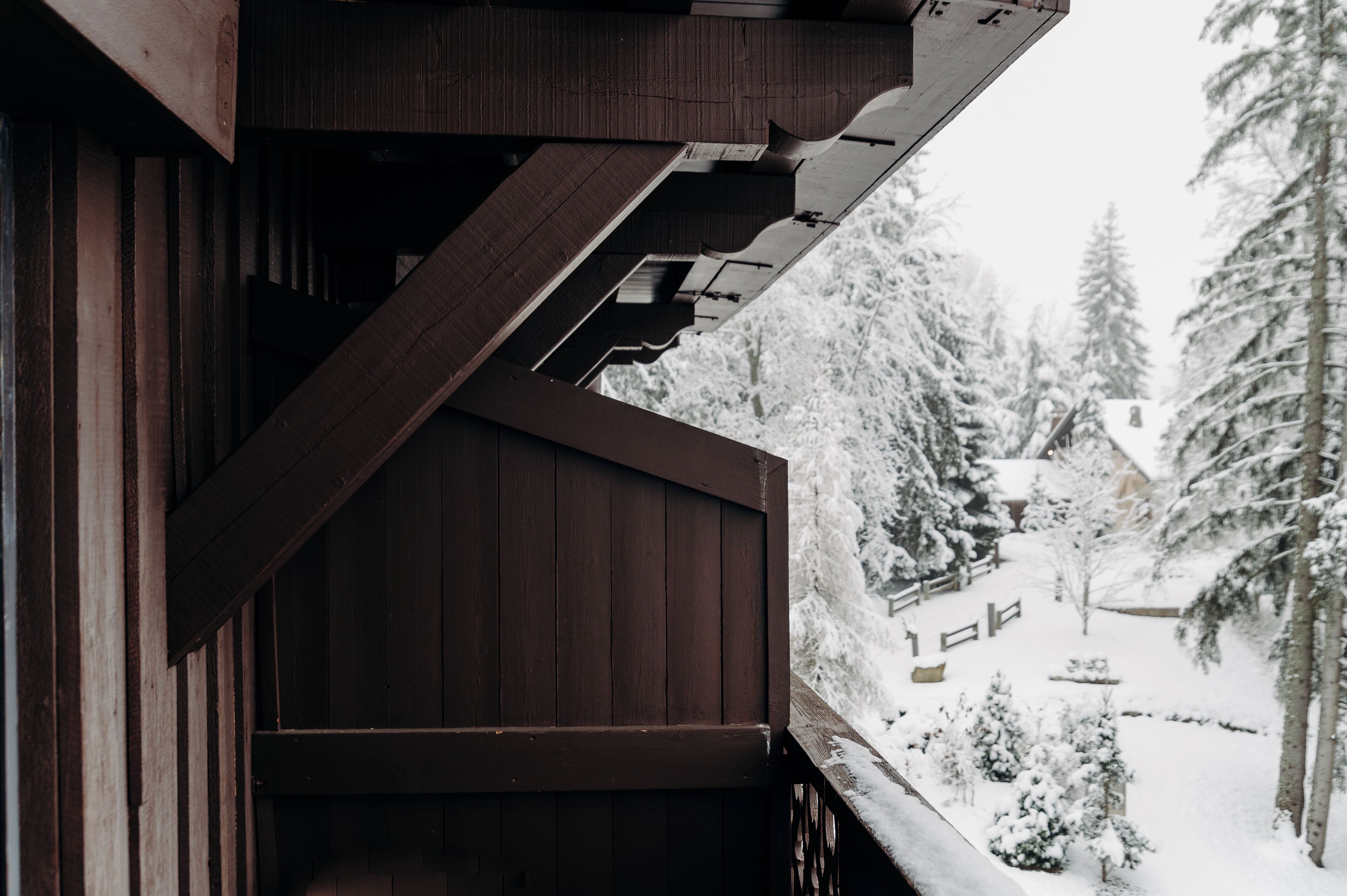 Ein hölzerner Balkon mit Blick auf eine verschneite Landschaft und Bäume.