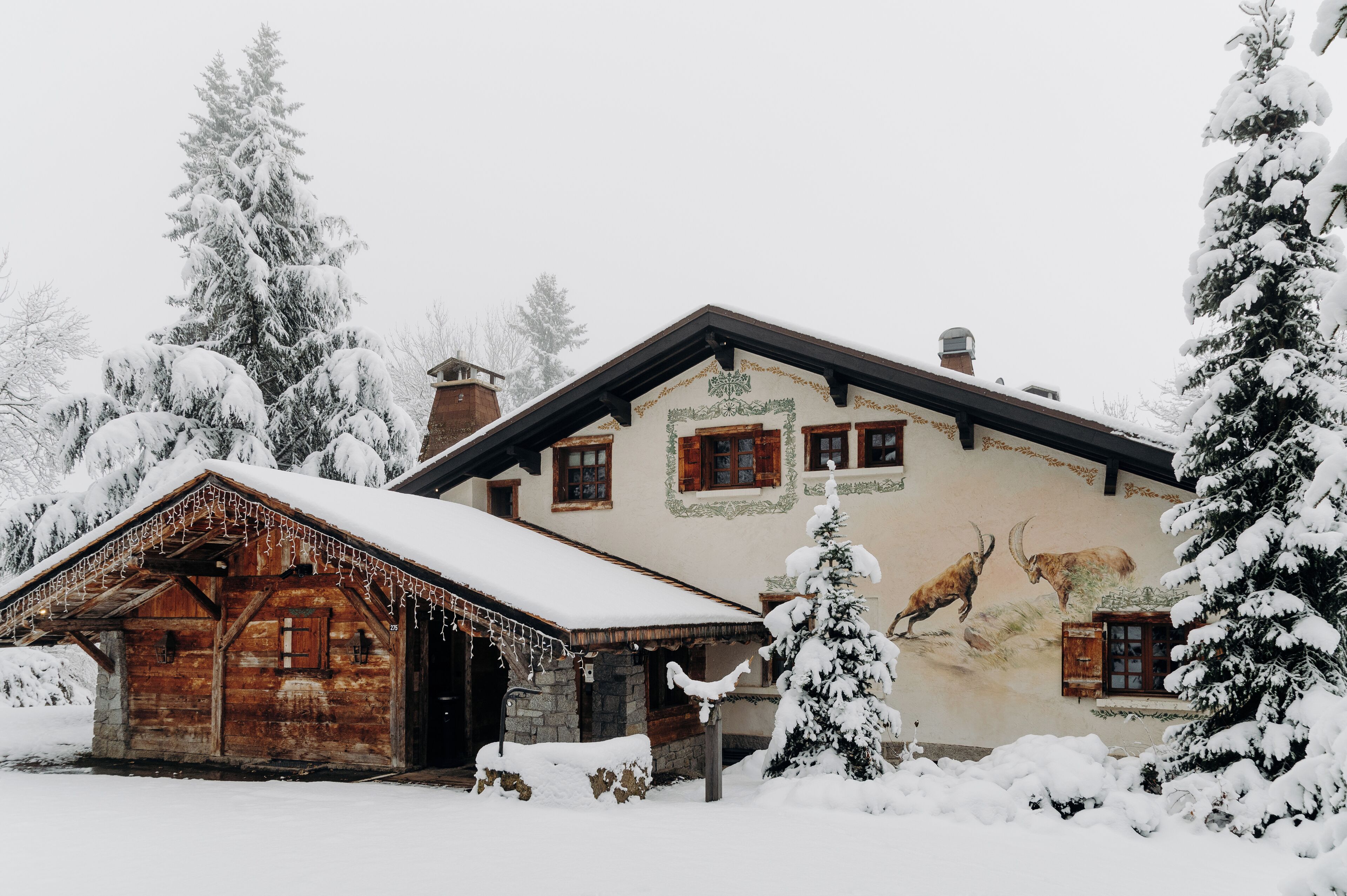 A rustic wooden building with a snow-covered roof and a mural of a mountain scene.