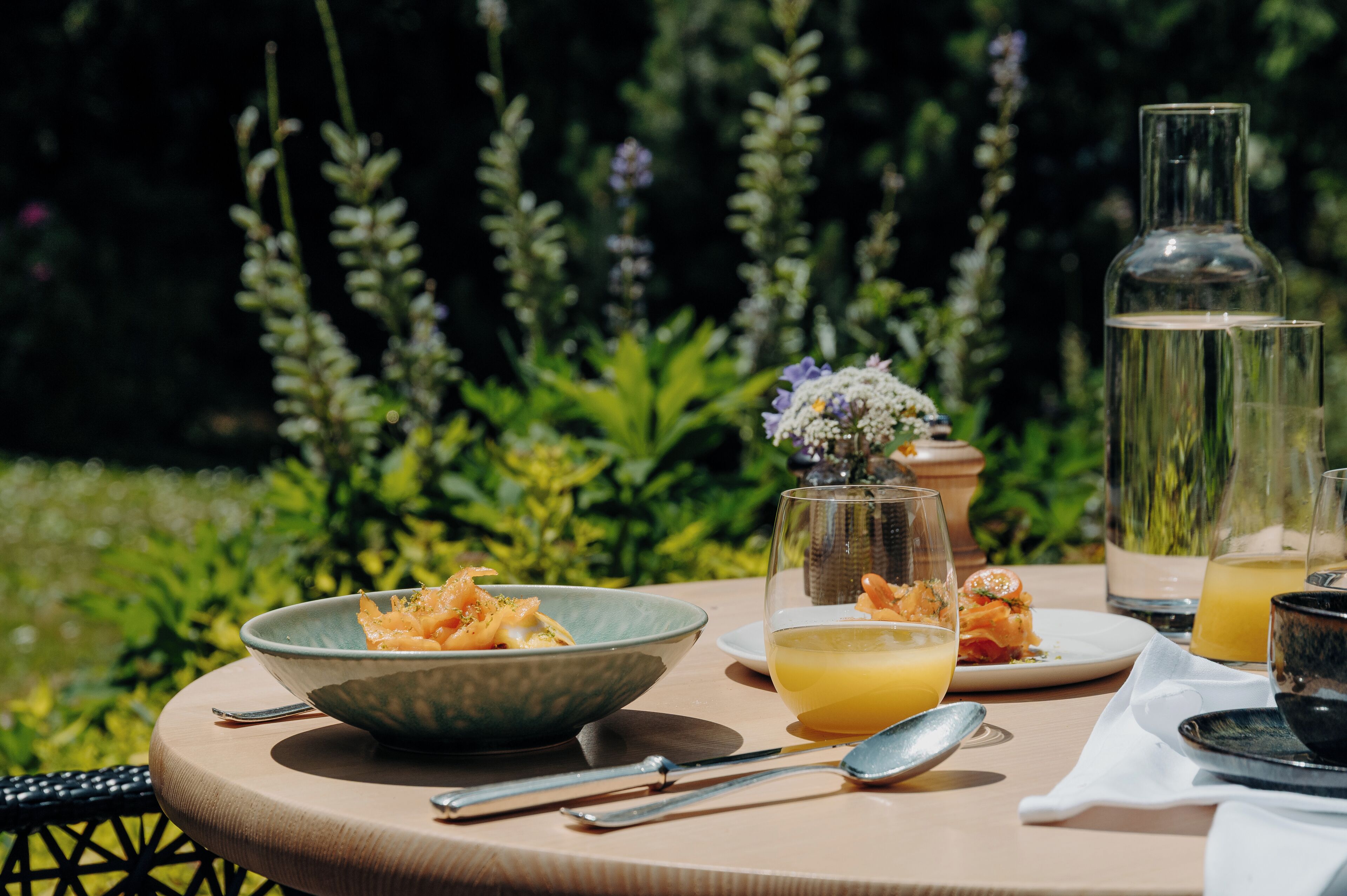 A round table with a bowl of food, a glass of orange juice, and a bottle of water.
