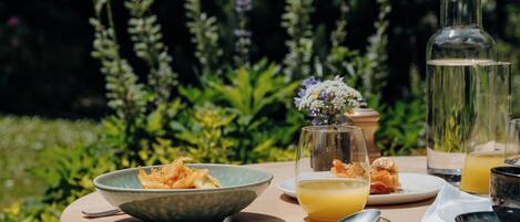 A round table with a bowl of food, a glass of orange juice, and a bottle of water.