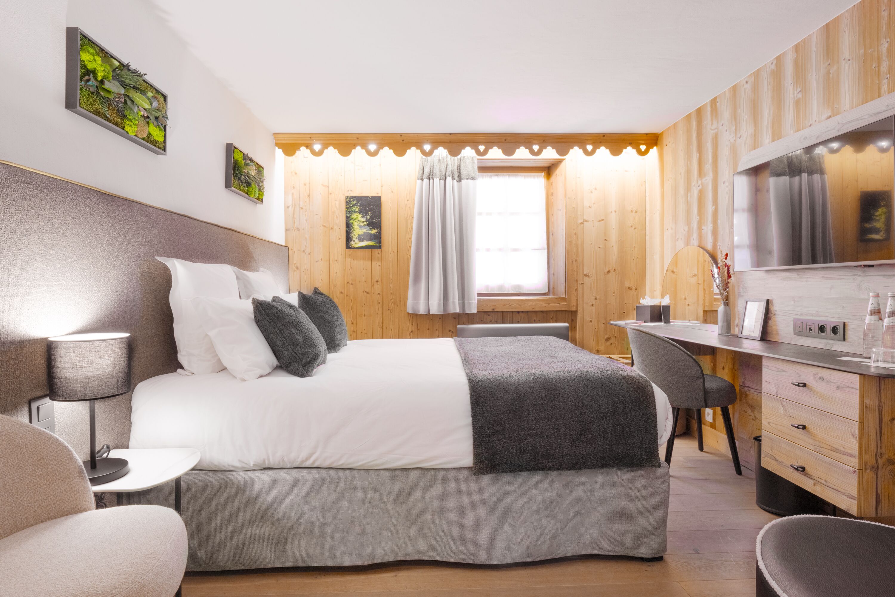 Een moderne slaapkamer met een bed, nachtkastje, lamp en een bureau met stoel.