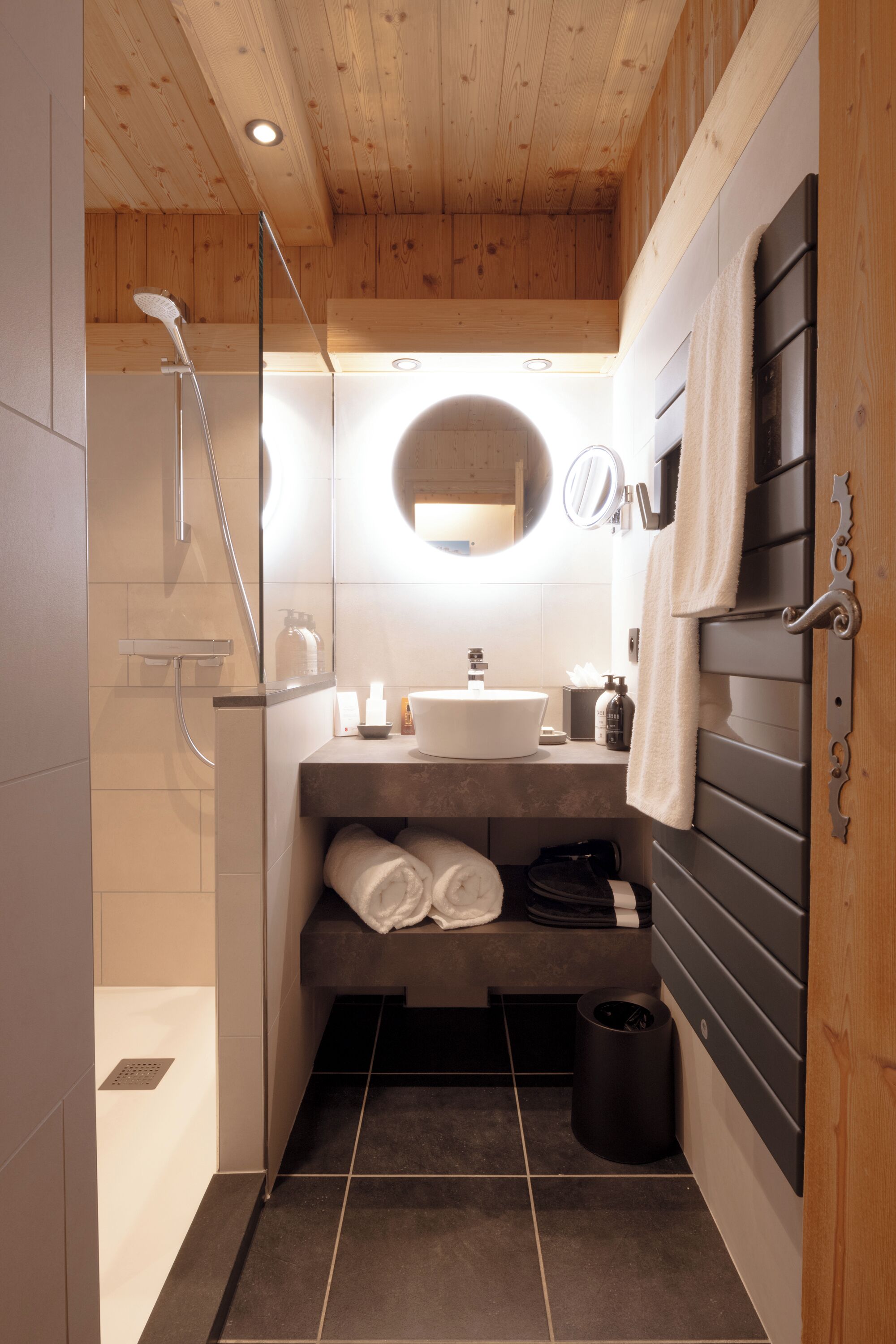 A compact bathroom with a shower, sink, and mirror.