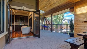 An open patio with a wooden ceiling, a dining table, a hammock, and a view of the outside. - Westmount River Inn (Calgary)