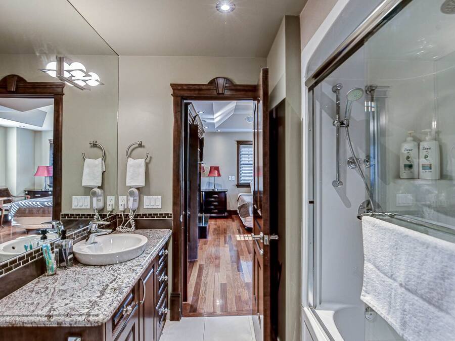Un baño moderno con ducha de vidrio, tocador doble y un espejo grande.