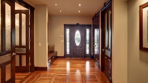 A hallway with wooden flooring and a dark wooden door with glass panels. - Westmount River Inn (Calgary)