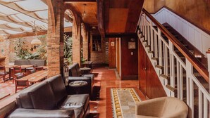 A spacious lobby with a high ceiling, wooden staircase, and comfortable seating areas. - Dunn Inn (San José)