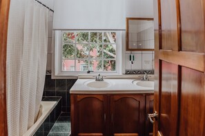 Un baño con dos lavamanos, una ventana con vistas a edificios y un armario de madera.