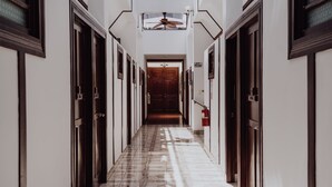 A long, narrow hallway with wooden doors on both sides, leading to a central door at the end. - Dunn Inn (San José)