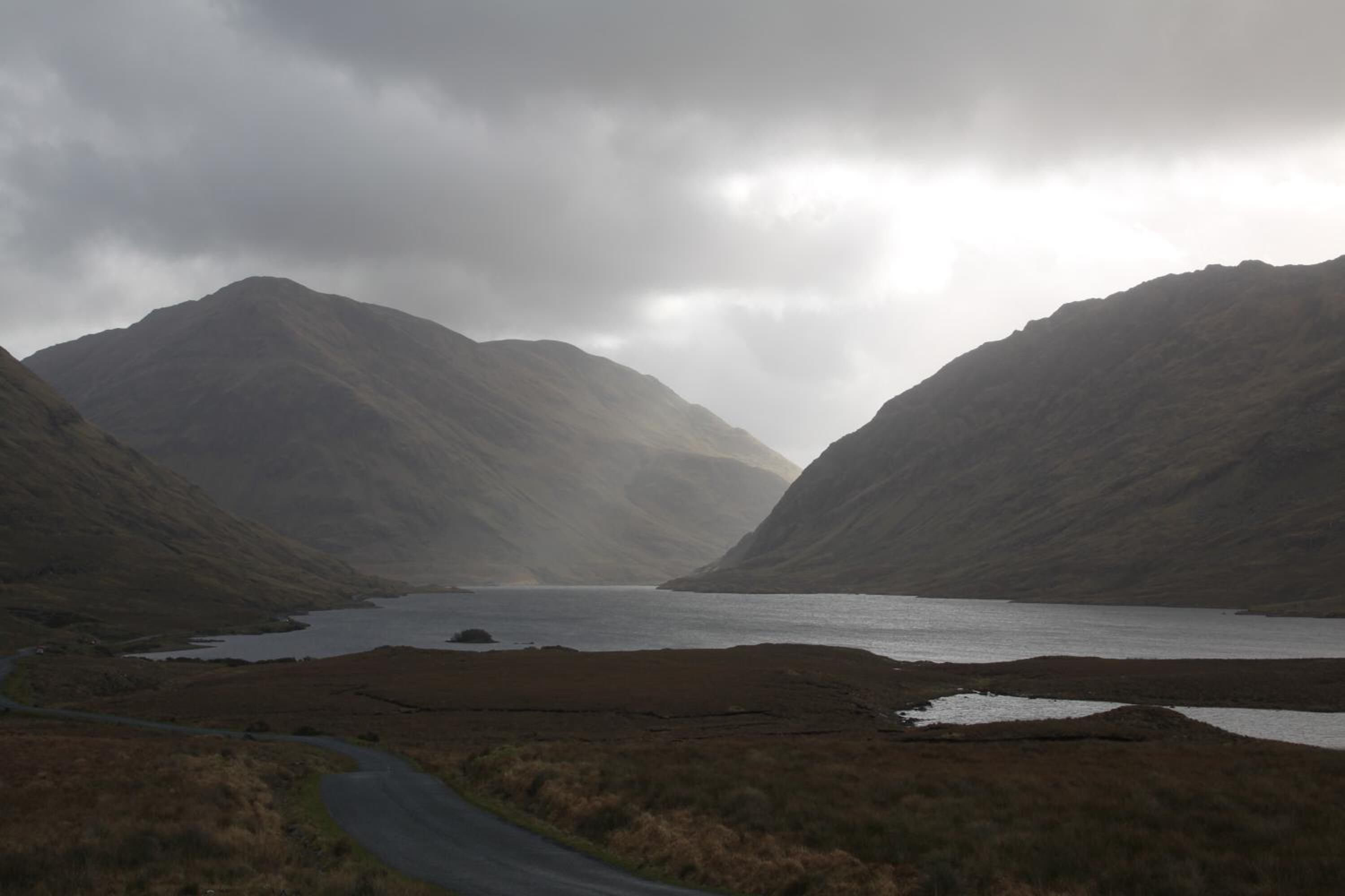 A mountainous landscape with a winding road and a body of water.