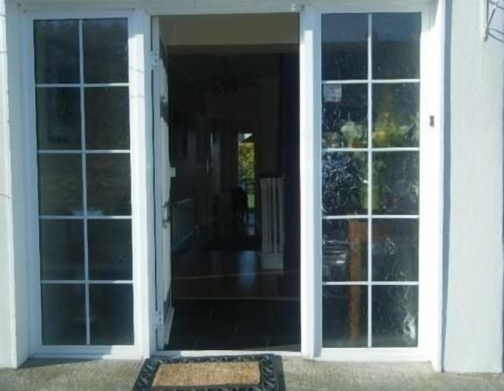 A building entrance with a glass door and a doormat.