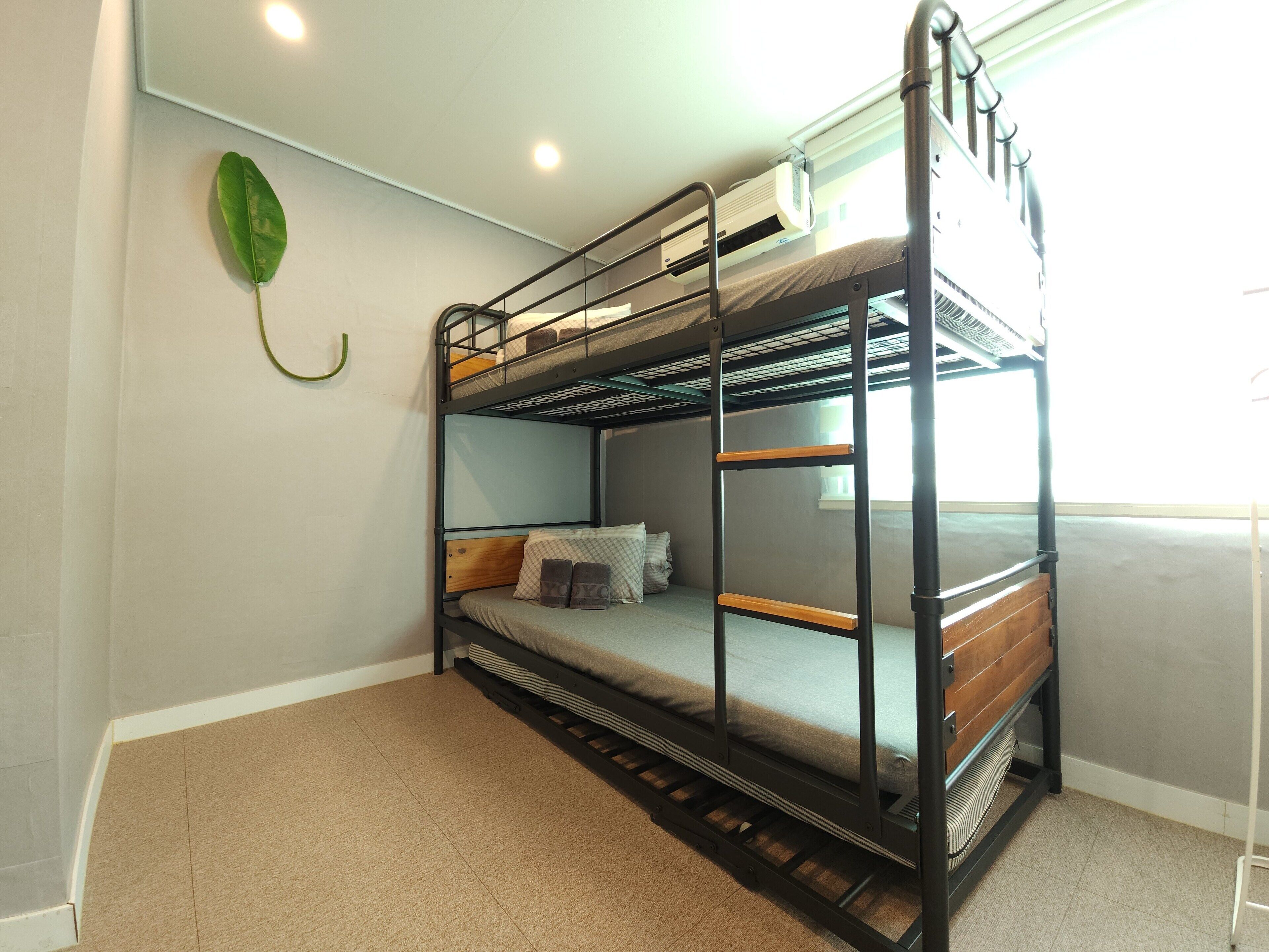 Una cama litera con cabecera de madera, una mesita de noche pequeña y una sola almohada.