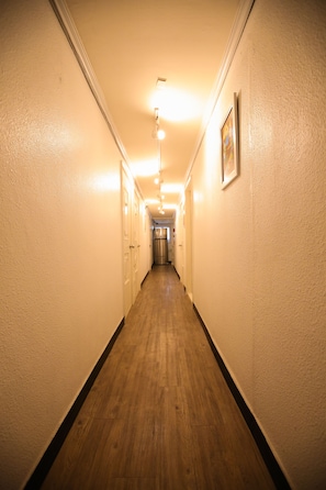 Ein Flur mit Holzboden, weißen Wänden und einem gerahmten Bild an der rechten Wand.