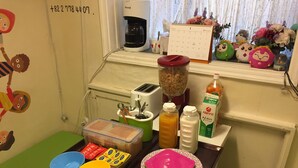 Un comptoir de cuisine sur lequel on trouve divers objets, notamment une machine à café, un calendrier et des récipients alimentaires.