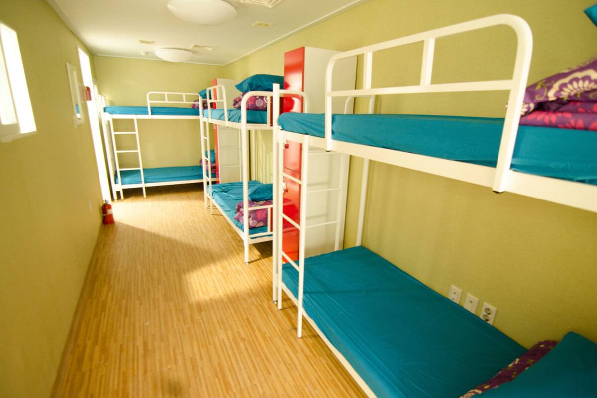 A room with bunk beds, wooden flooring, and a window.