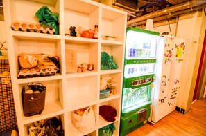 Una cocina con estantes blancos, un refrigerador verde y una máquina expendedora.