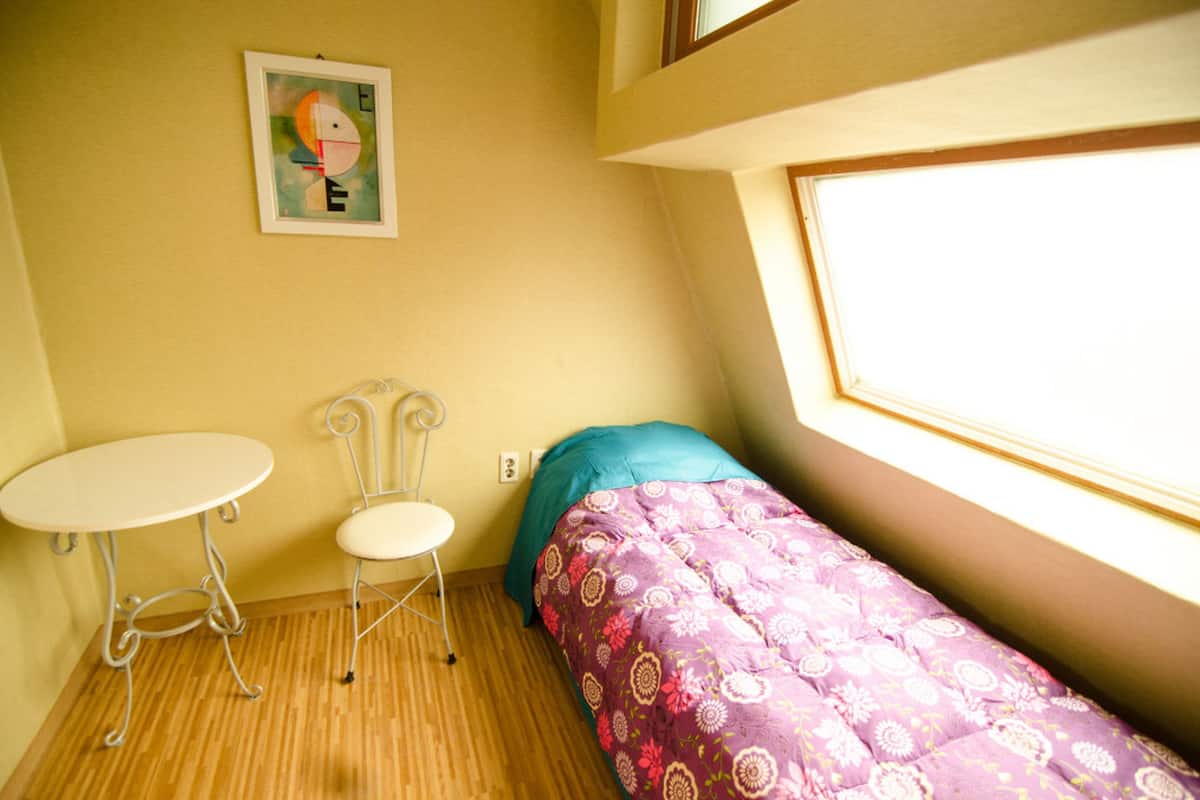 A small room with a bed, a table, and a chair.