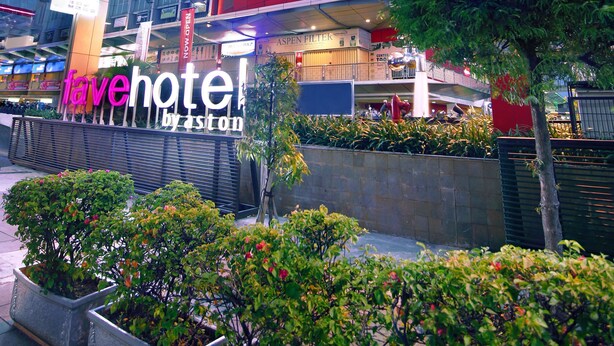 Een modern hotel met een gebogen gevel, meerdere verdiepingen en een opvallend bord met de tekst 'fave hotel by aston'.