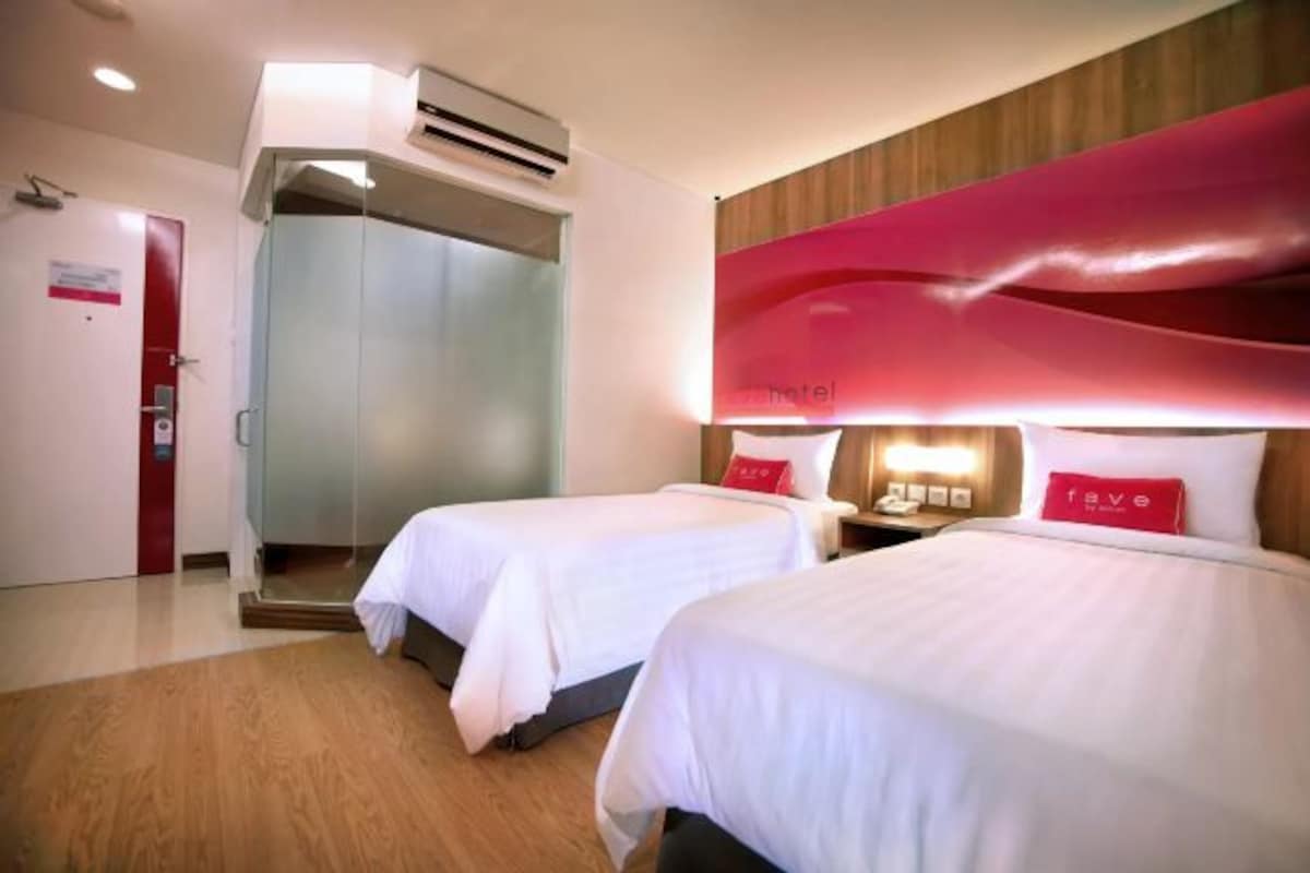 Une chambre d’hôtel avec deux lits, un mur d’accent rouge et un design moderne.