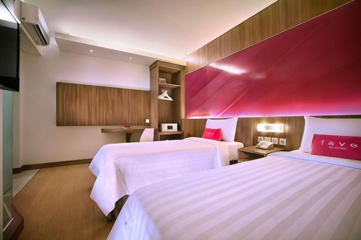 A hotel room with two beds, a desk, and a wardrobe.