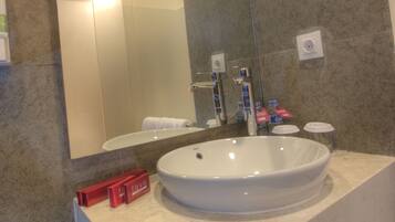 A bathroom with a large mirror, a white sink, and a towel hanging on the wall.
