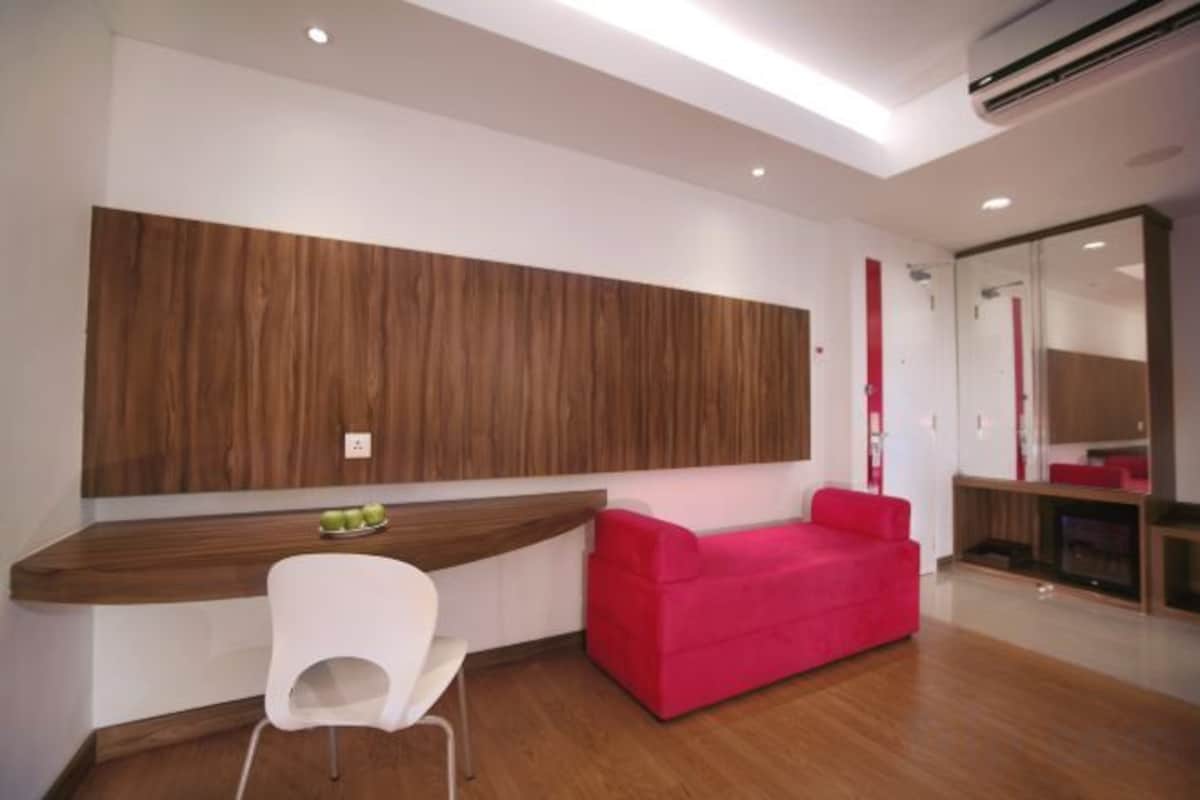 A modern room with a wooden accent wall, a white chair, a red sofa, and a large mirror.