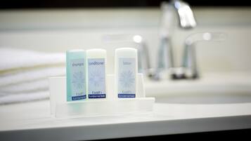 Un ripiano del bagno con tre flaconi di articoli da toilette etichettati shampoo, balsamo e lozione.