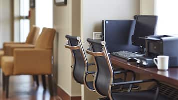 Una habitación de hotel con escritorio, dos sillas, un ordenador y una taza de café.