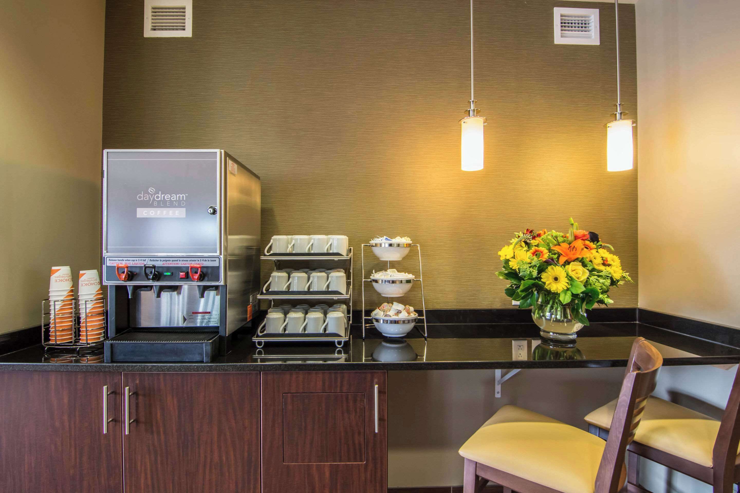 A coffee station with a DayDream blend coffee machine, multiple coffee cups, and a flower vase.