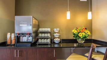 A coffee station with a DayDream blend coffee machine, multiple coffee cups, and a flower vase.