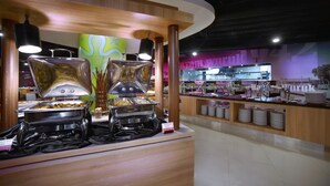 Un espace buffet doté de plusieurs points de service, une cuisine située à l’arrière-plan et un aménagement propre et moderne.