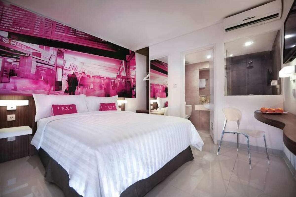 Ein modernes Hotelzimmer mit einem großen Bett, einem Schminktisch mit Spiegel und einer Sitzecke.