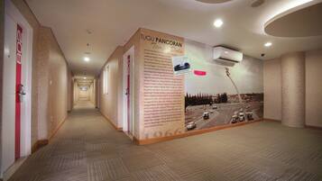 Un pasillo con un gran panel informativo sobre Tugu Pancoran, que muestra fotografías históricas y texto.