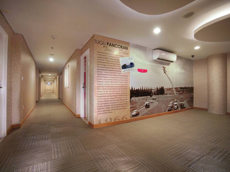 Un pasillo con un gran panel informativo sobre Tugu Pancoran, que muestra fotografías históricas y texto.