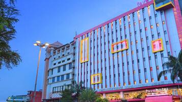 Stylish hotel building with a prominent entrance, offering a mix of glass and solid panels, and multiple floors with balconies.