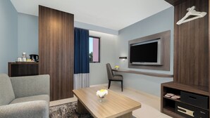 Un salon moderne avec un canapé, une table basse agrémentée d’un vase, un téléviseur fixé au mur et un meuble en bois.