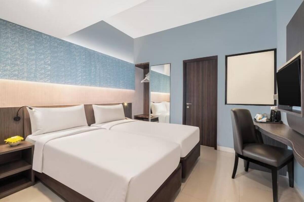 Een hotelkamer met een groot bed, een bureau, een stoel, een televisie en een kledingkast.