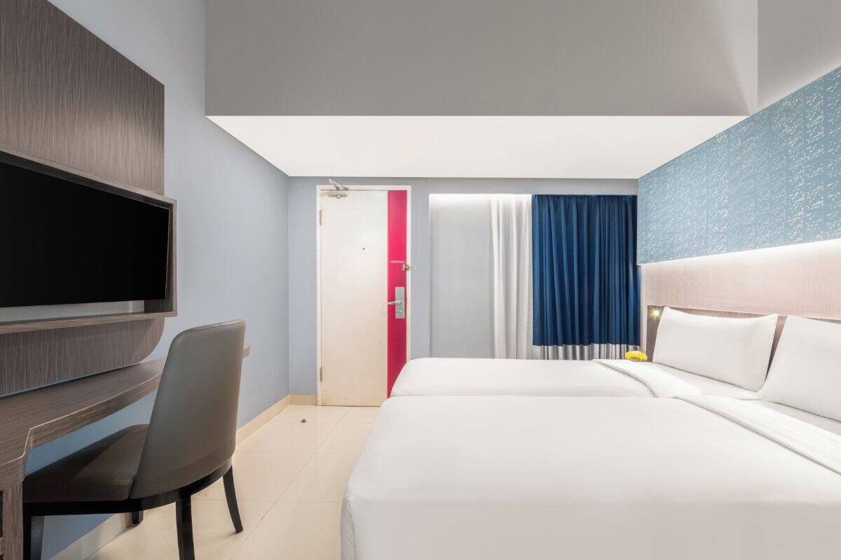 Een hotelkamer met een bed, een bureau, een televisie en een deur naar een badkamer.