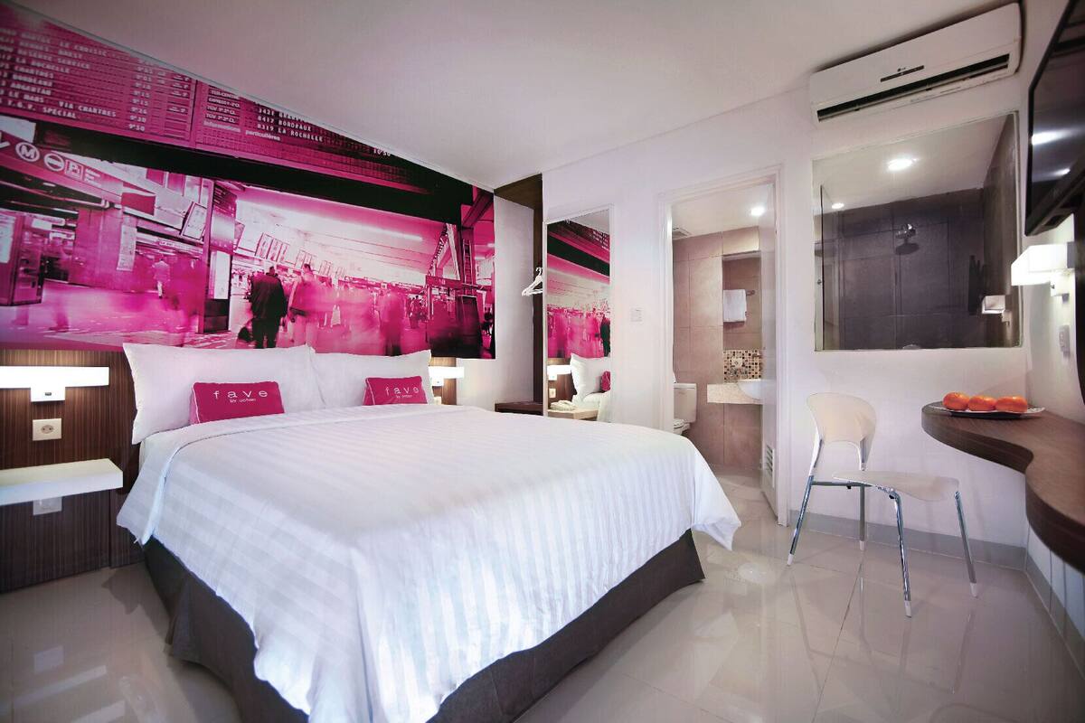 Een moderne hotelkamer met een groot bed, een kaptafel met spiegel, een zithoekje en uitzicht op de stad.
