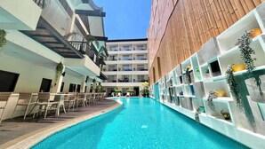Un hotel moderno con piscina central, varios balcones y zonas de estar interiores.