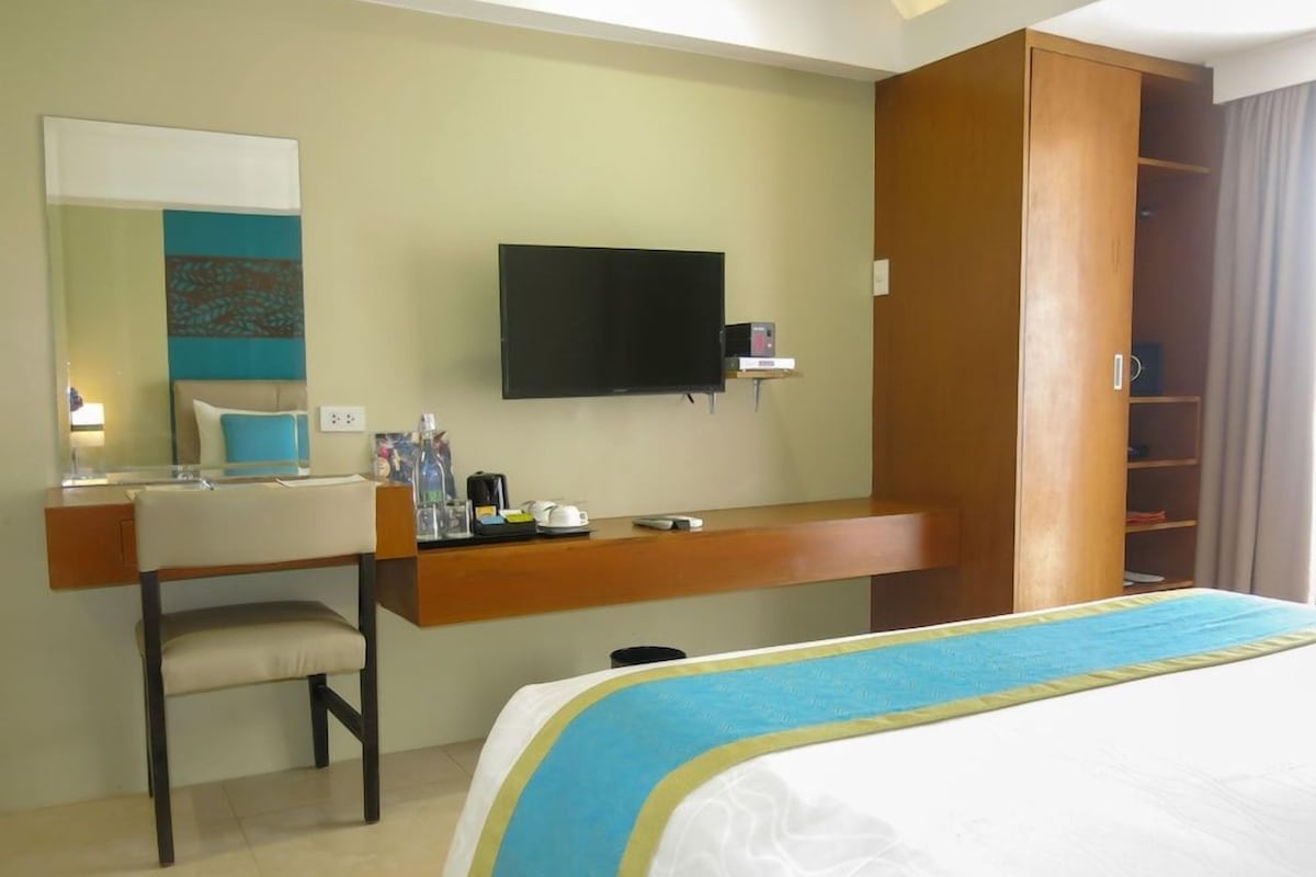 Une chambre d’hôtel comprenant un lit, un bureau avec une chaise, une télévision et une armoire.