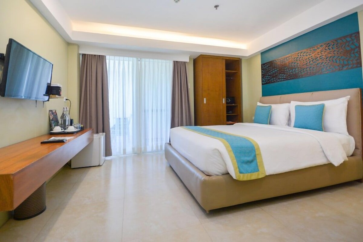 Une chambre d’hôtel avec un lit, un bureau, une télévision et une armoire.