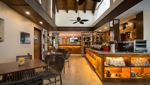 Una cocina moderna con barra, techo de madera y un televisor al fondo.