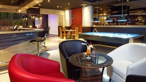 Een moderne lounge met een pooltafel, comfortabele zitplaatsen en sfeerverlichting.