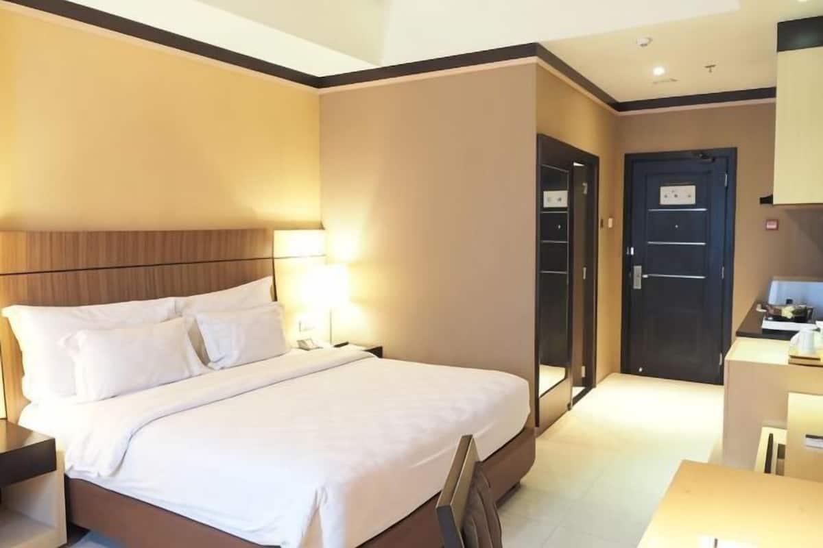 Une chambre d’hôtel comprenant un lit, une table de chevet, une lampe et une porte donnant accès à une salle de bain.