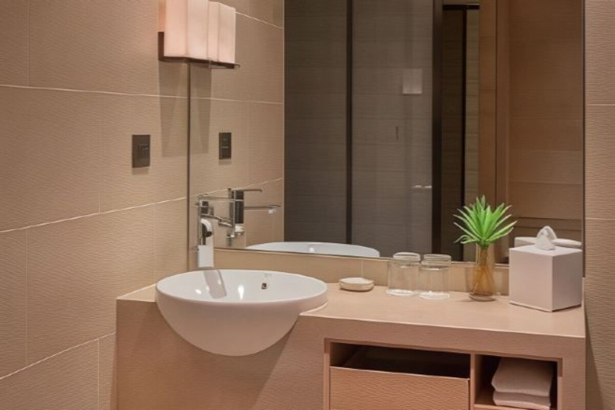 Un baño moderno con un lavamanos grande, un espejo y una planta pequeña en el mueble.