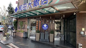 Entrada de un hotel con un corredor cubierto, un letrero que indica que es el Mr. Hotel, y un diseño arquitectónico tradicional chino.