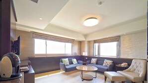 Una sala de estar moderna con un conjunto de sofá, una mesa de centro y una zona de estar con una lámpara.