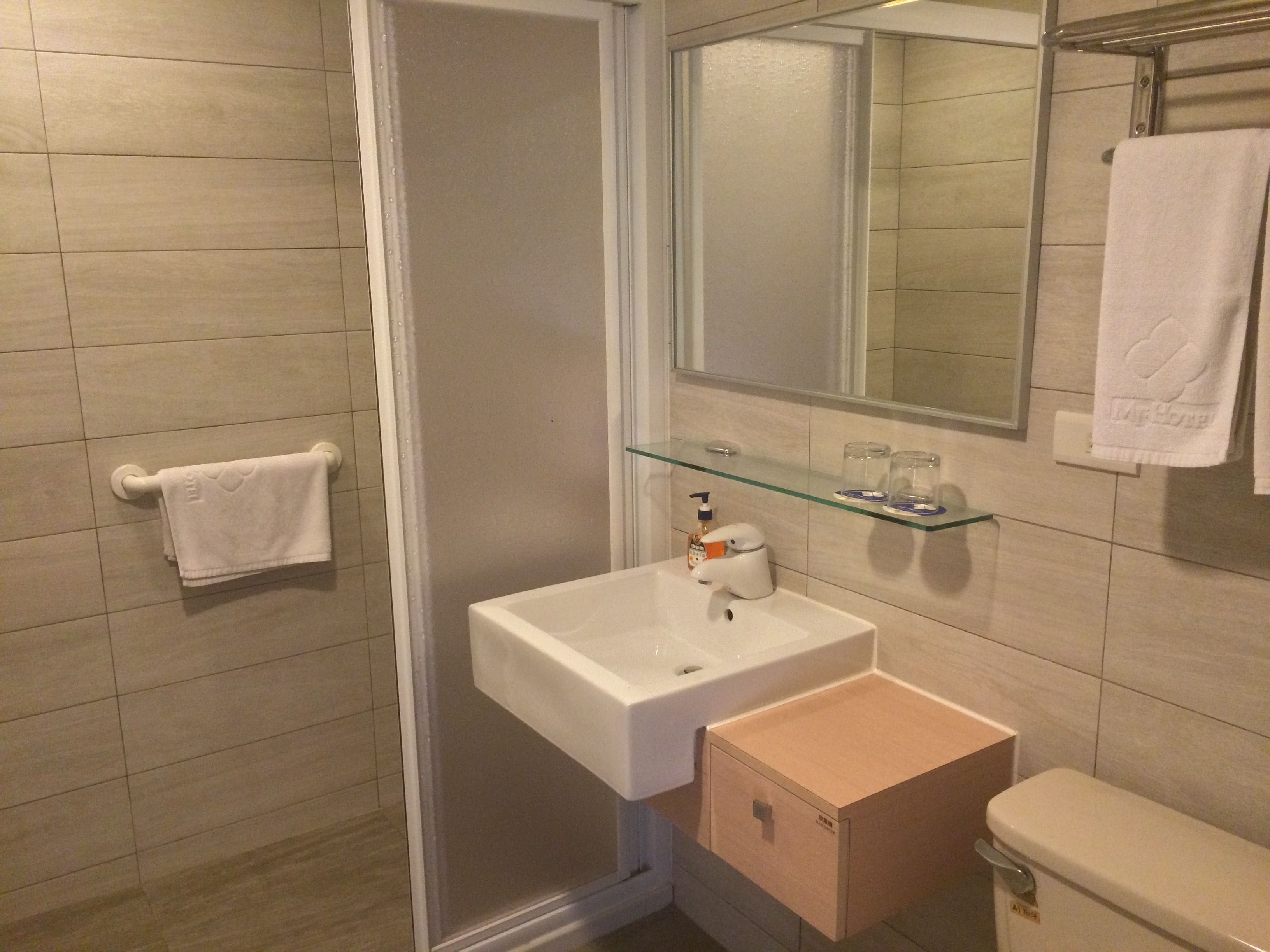 A bathroom with a glass shelf, a white sink, and a toilet.