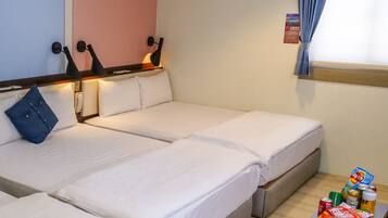 A hotel room with three beds, a small table with snacks, and a window with curtains.